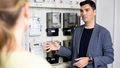 Energy systems researcher Philipp Staudt is being interviewed and points to the electricity meter next to him while describing his research goals. 