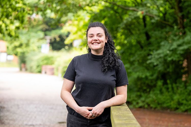 Das Bild zeigt Magali Roberts. Sie steht auf einer Holzbrücke am Campus Wechloy und lächelt in die Kamera.