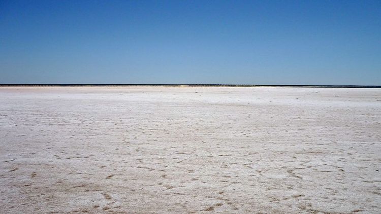 Landscape: Smooth, white background (the salt), blue sky above, in the background a thin, darker stripe on the horizon.
