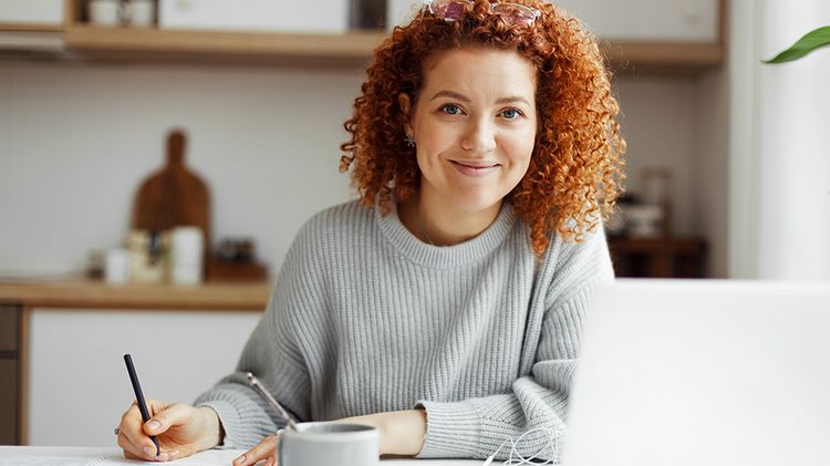 A young woman works on a laptop in a modern office.