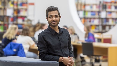 Young man in front of the background of the large hall on the first floor of the university library.                                        -Library.