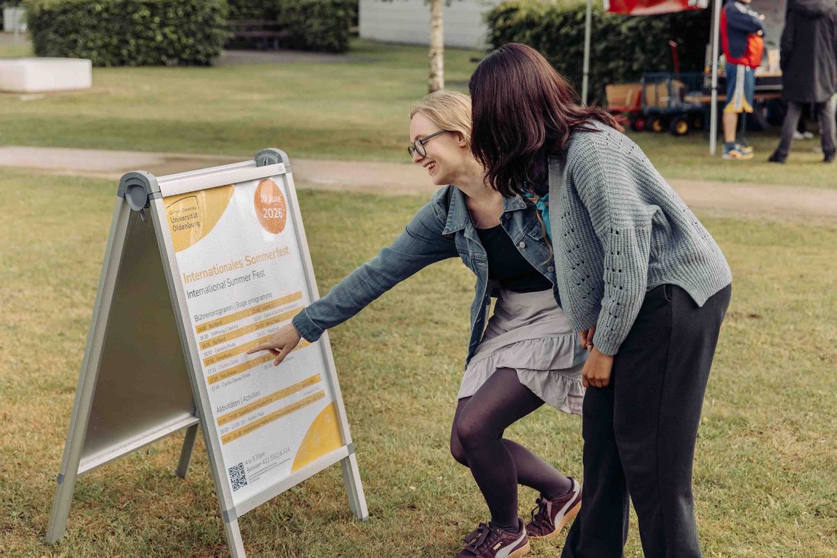 Zwei Personen besprechen den Programmaufsteller zum Sommerfest.