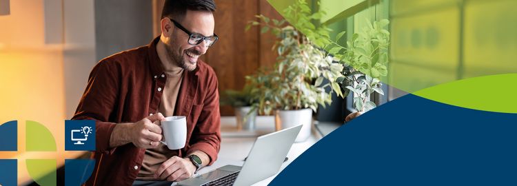 A man holds a coffee cup and looks at a laptop.