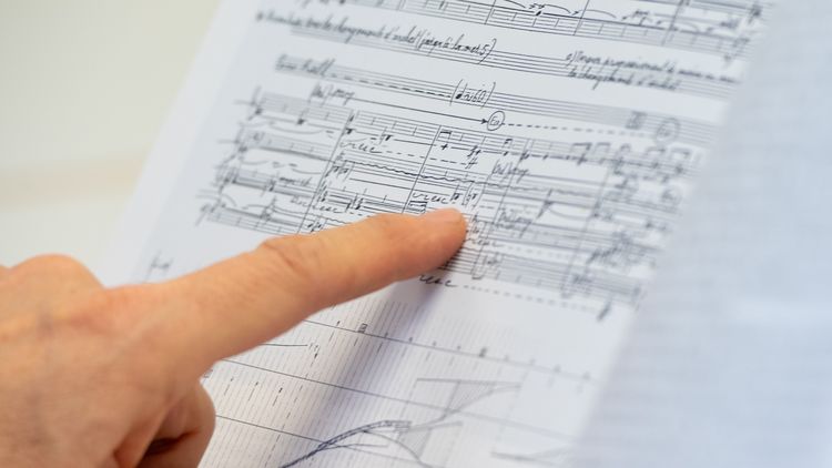 Foto einer Hand, die auf ein Notenblatt mit Neuer Musik zeigt.
