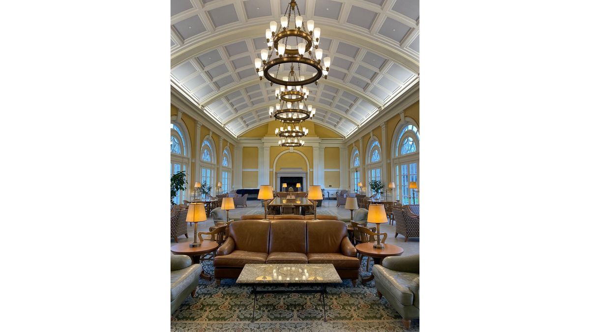 Eleganter, heller Salon mit Ledersofas, Kronleuchtern und großen Fenstern.