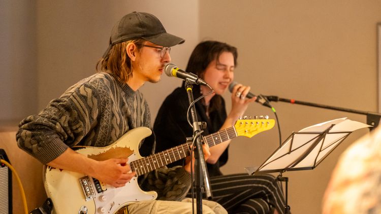Ein Musik-Duo spielt live auf der Bühne Gitarre und Gesang.