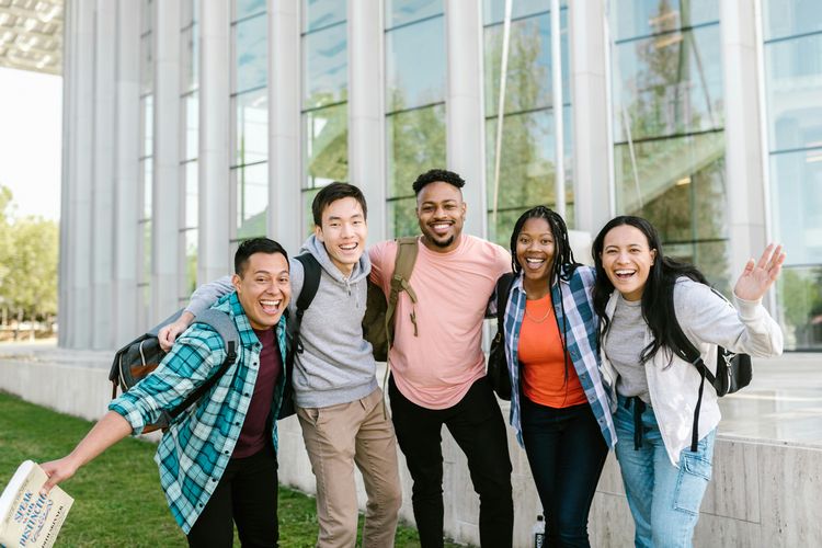 A group of five young people posing and smiling for the camera.