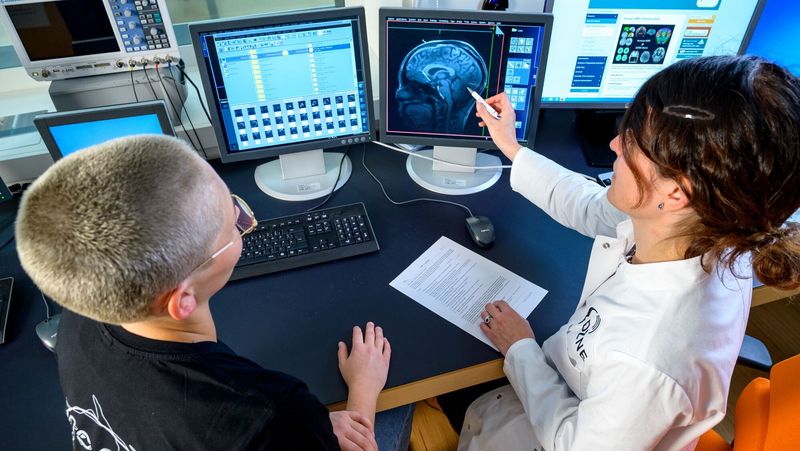 Zwei Personen sitzen vor einem Monitor und betrachten einen Hirnscan.