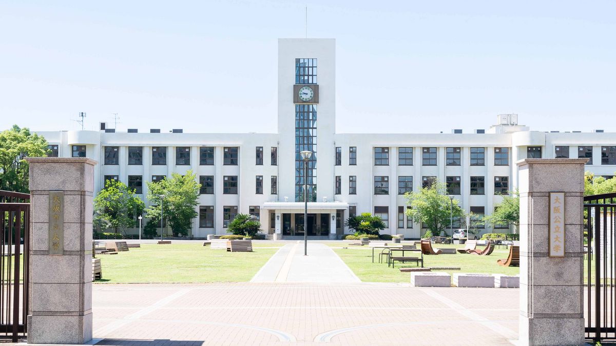 A white building complex of Osaka Metropolitan University with a striking clock tower and manicured lawns.