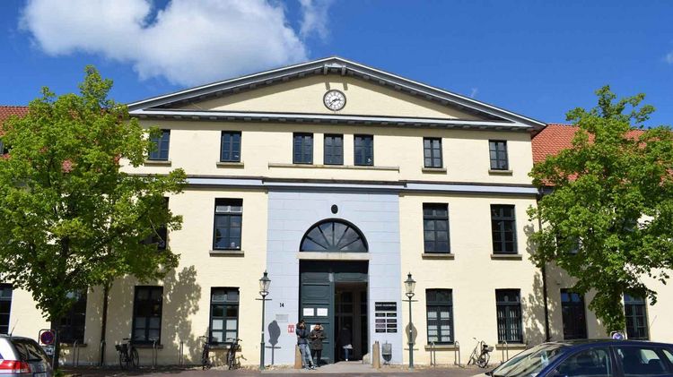 The citizen's office in the city center of Oldenburg with a light-colored facade, clock and arched window.