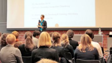 Personen sitzen in einem Saal und hören sich einen Vortrag an.