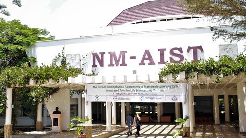 Two peole are walking towards the entrance of the building.