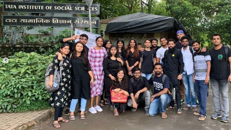 Eine Gruppe von Menschen posiert vor einem Schild des Tata Institute of Social Sciences.