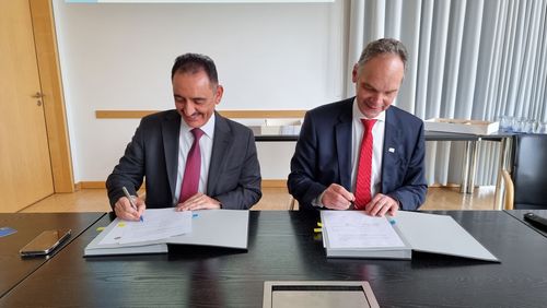  Foto des Präsidenten der Universität Mossul, Irak, und des Präsidenten der Universität Oldenburg in den Räumen der Universität Oldenburg. Die beiden Präsidenten sitzen gemeinsam an einem Tisch und unterzeichnen ein Dokument (Memorandum of Understanding).