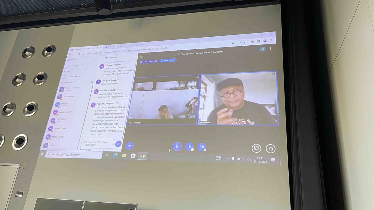 A video conference on a screen, with several participants and a man speaking.