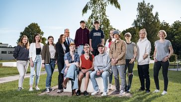 Eine Gruppe junger Menschen sitzend und stehend auf dem Campus der Universität