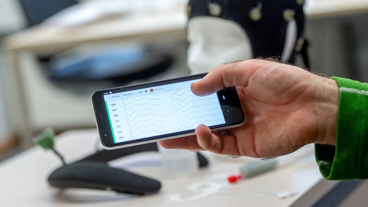 Wave-shaped EEG measurement data can be seen on a smartphone display.