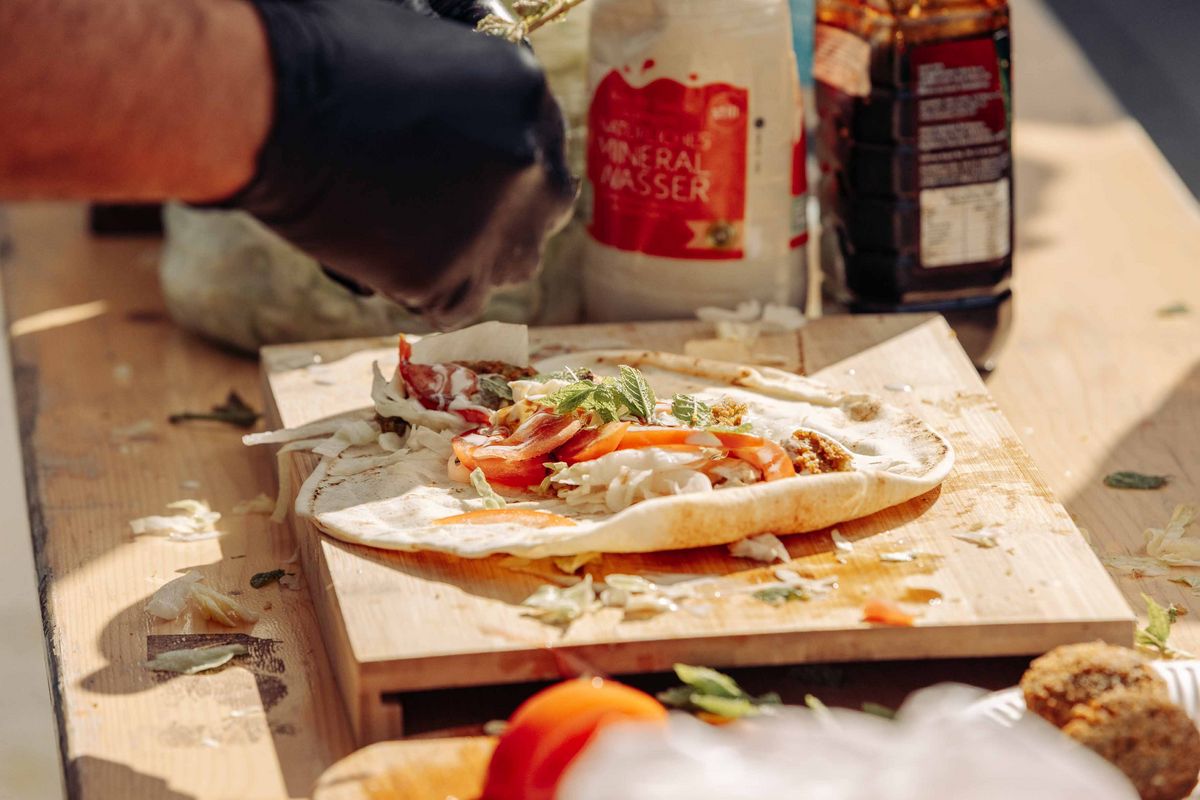 Ein ungerolltes Fladenbrot mit Falafel und Beilagen.