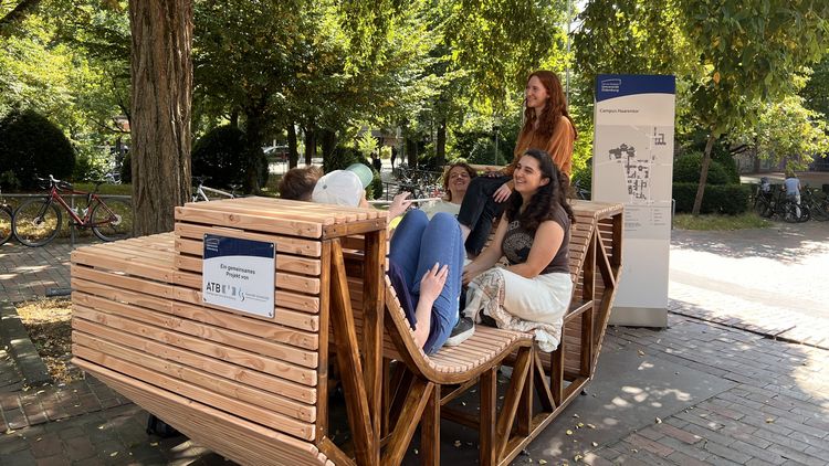 Studierende sitzen auf Sitzbänken.