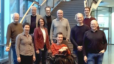 Twelve people stand next to each other on a staircase.