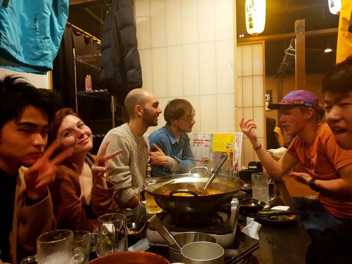 Studierende die Spaß haben und sich lachend unterhalten, abends in einem Restaurant in Sendai. 