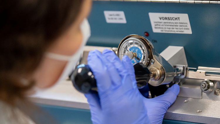A woman is working on a mechanical device on which a scale can be seen.