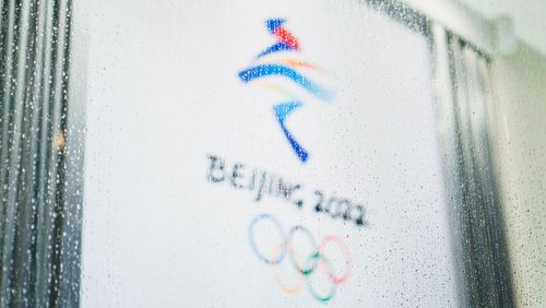 Olympia-Logo hinter einer mit Regentropfen benetzen Scheibe.