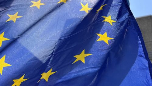Nahaufnahme einer EU-Flagge mit gelben Sternen auf blauem Grund.