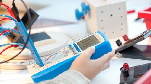 Child holding a measuring device connected to some cables.