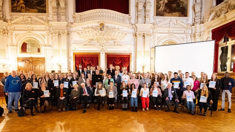 Das Bild zeigt Vizepräsidentin Al-Shamery, die Geförderten sowie die Fördererinnen und Förderer im Prunksaal des Oldenburger Schlosses. Sie stehen vor einer Wand mit dem Wappen des Landes Oldenburg. Sie halten ihre Urkunden in den Händen und lächeln in die Kamera.