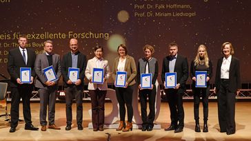 The people stand next to each other on the stage with their certificate in their hands.