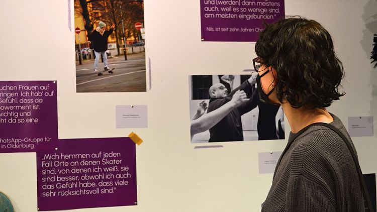 Eine Besucherin betrachtet Bilder und Texte auf einer Ausstellungswand.