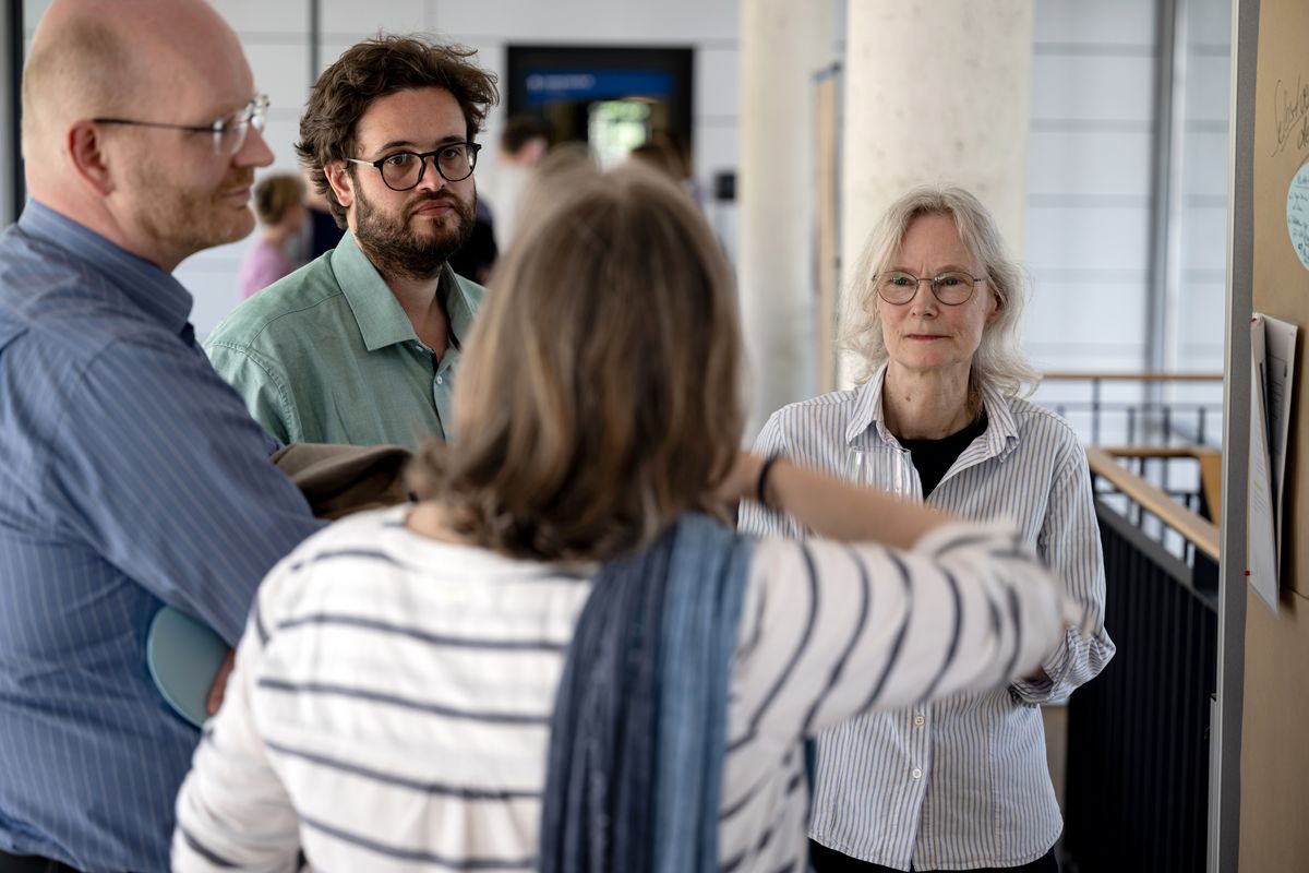 Das Foto zeigt vier miteinader sprechende Personen in der Gruppenarbeitsphase vor einer beschriebenden Stellwandzum beim ersten Sustainability Sounding Boards des universitären Klimaschutzmanagements.