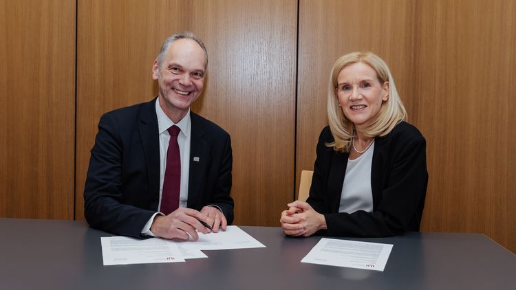 Ralph Bruder and Jutta Günther with contract documents in a meeting room—both looking friendly at the camera.