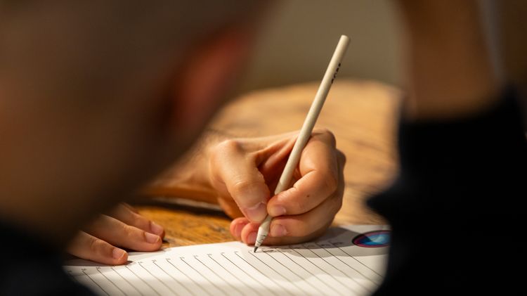 Nahaufnahme einer Hand mit einem Stift, die einen Antwort-Zettel ausfüllt
