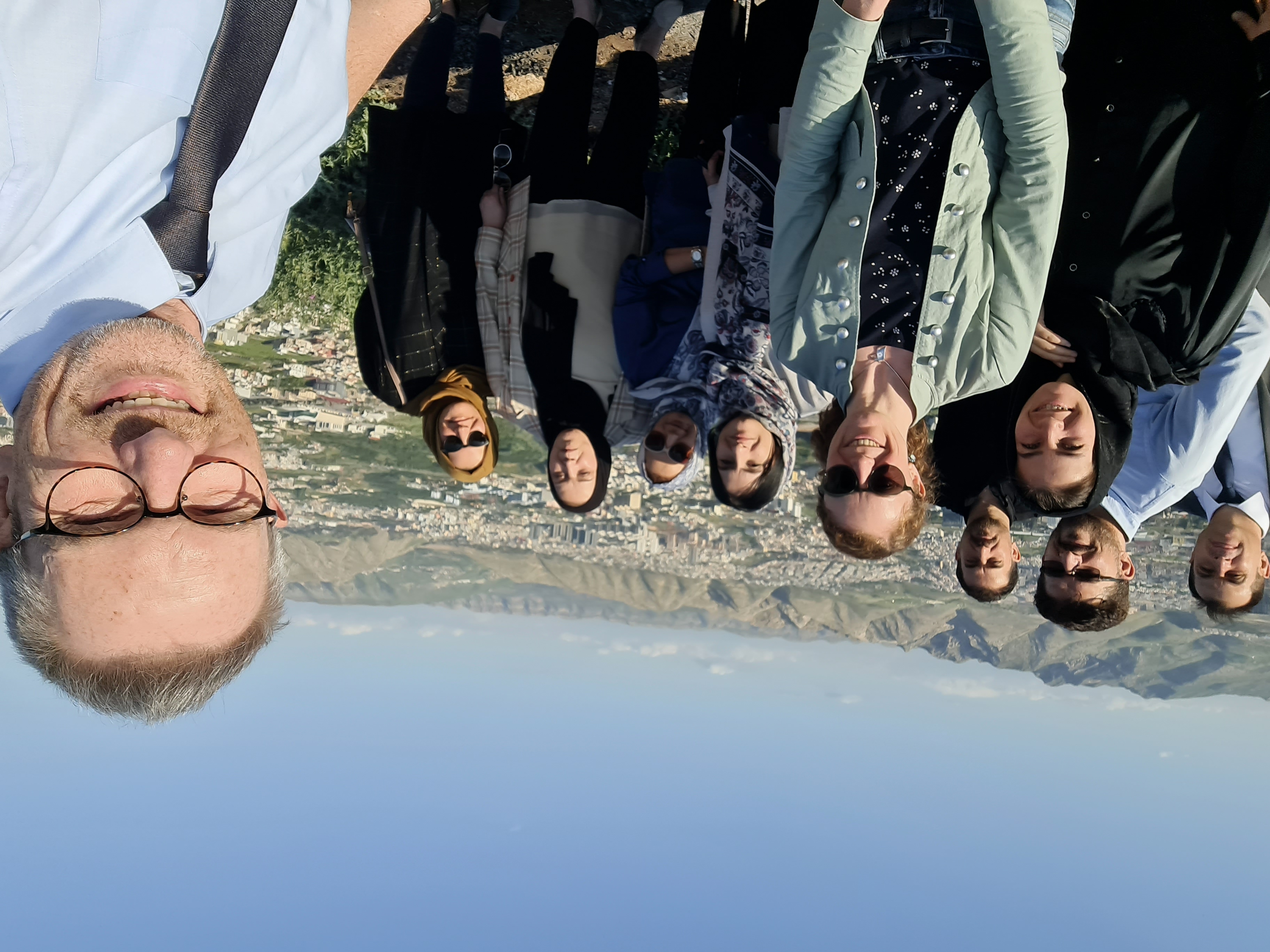 The picture shows Clemens Hillenbrand and nine other project participants. A city and mountains can be seen in the background. The picture is a selfie.
