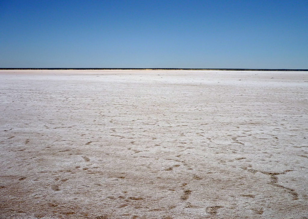 Landscape: Smooth, white background (the salt), blue sky above, in the background a thin, darker stripe on the horizon.